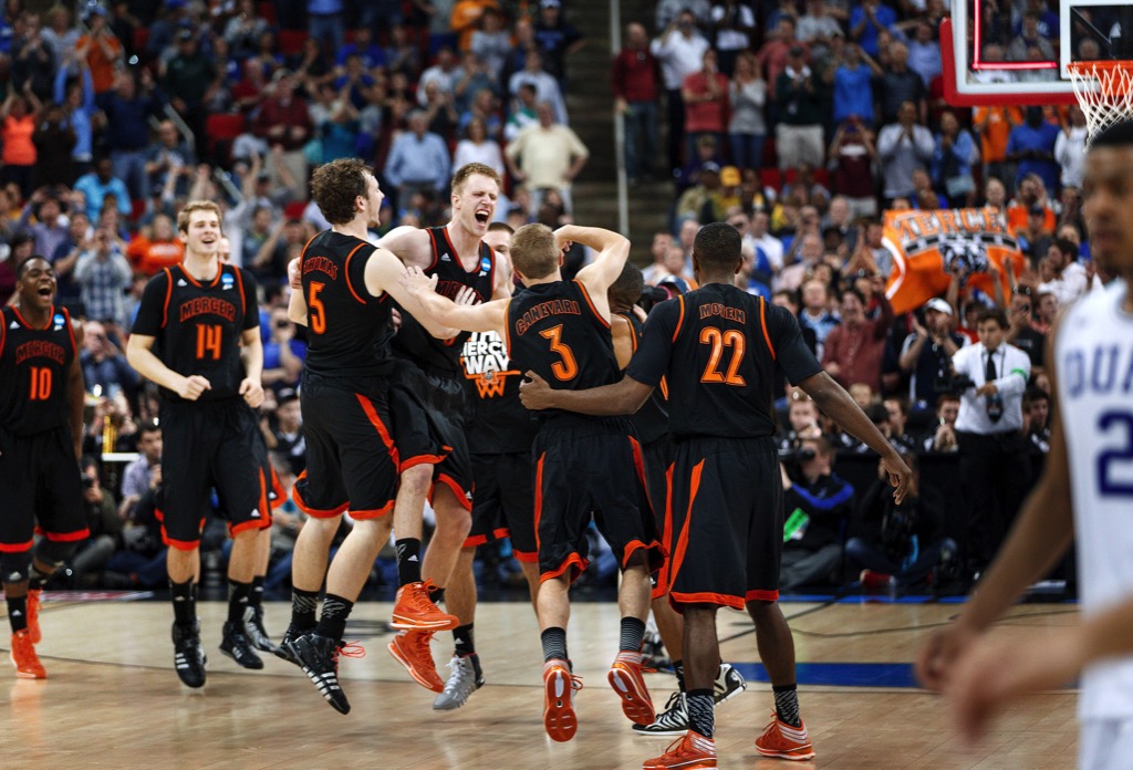 Mercer forward Jakob Gollon (20), center, and the Mercer team celebrate their 78-71 victory as Duke guard Quinn Cook (2) walks off the court. Mercer asMercer vs. Duke in a second-round game in the NCAA college basketball tournament at the PNC Center on Friday, March 21, 2014, in Raleigh, N.C.